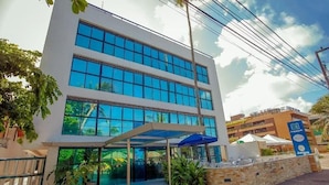 A modern building with large glass windows, a covered entrance, and a sign for 'Jampa'. - Ambassador (João Pessoa)