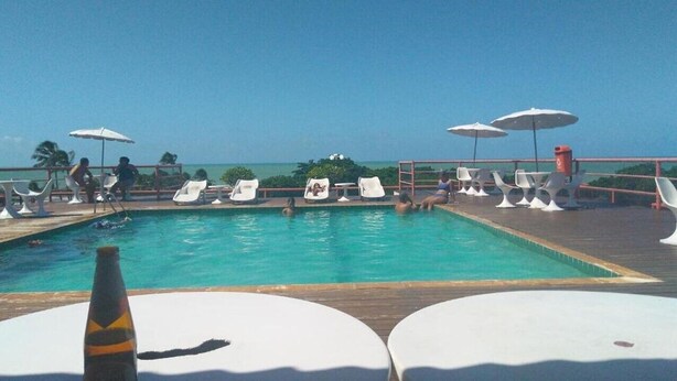 Poolbereich mit Liegestühlen und Sonnenschirmen mit Blick auf den Ozean.