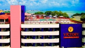 Ein Hotel mit mehreren Balkonen, einem gut sichtbaren Schild mit der Aufschrift "VICTORY" und Blick auf Strand und Meer.
