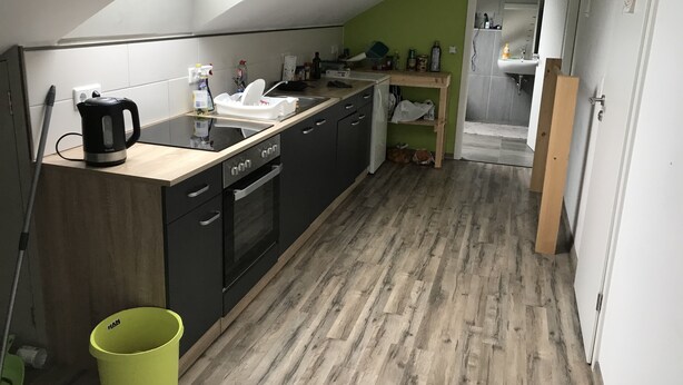 A compact kitchen with a skylight, wooden flooring, and a small dining area. - Single room (Homberg (Efze))