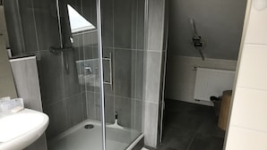 A modern bathroom with a glass-enclosed shower, a white sink, and a tiled floor. - Single room (Homberg (Efze))