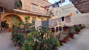 A courtyard with potted plants, a balcony with clothes hanging, and a building facade. - Domus Lou Luxury Apartment in Trastevere Rome (Roma)