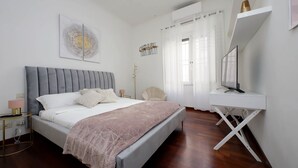 A modern bedroom with a bed, bedside table, chair, desk, and artwork. - Domus Lou Luxury Apartment in Trastevere Rome (Roma)