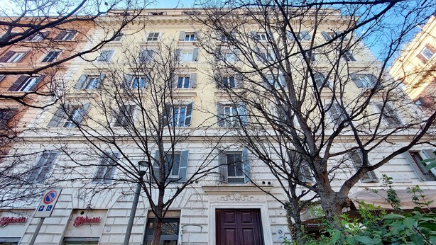 A building with a large wooden door, multiple windows, and a sign for 'Gatti'. - Domus Lou Luxury Apartment in Trastevere Rome (Roma)