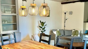 Un comedor con mesa de madera, sillas negras y lámparas colgantes.