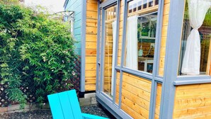 Una cabaña de madera con una ventana y una silla azul en el exterior.