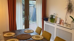 A dining area with a wooden table, woven placemats, and yellow chairs. - 3 bed house in East Ham , east london with a garden (London)