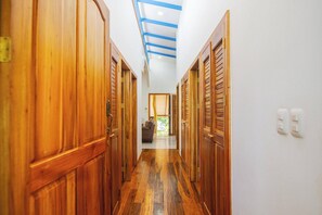Een gang met houten deuren en een plafond met blauwe balken.