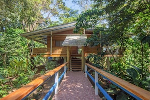 A wooden house with a balcony, surrounded by lush greenery.