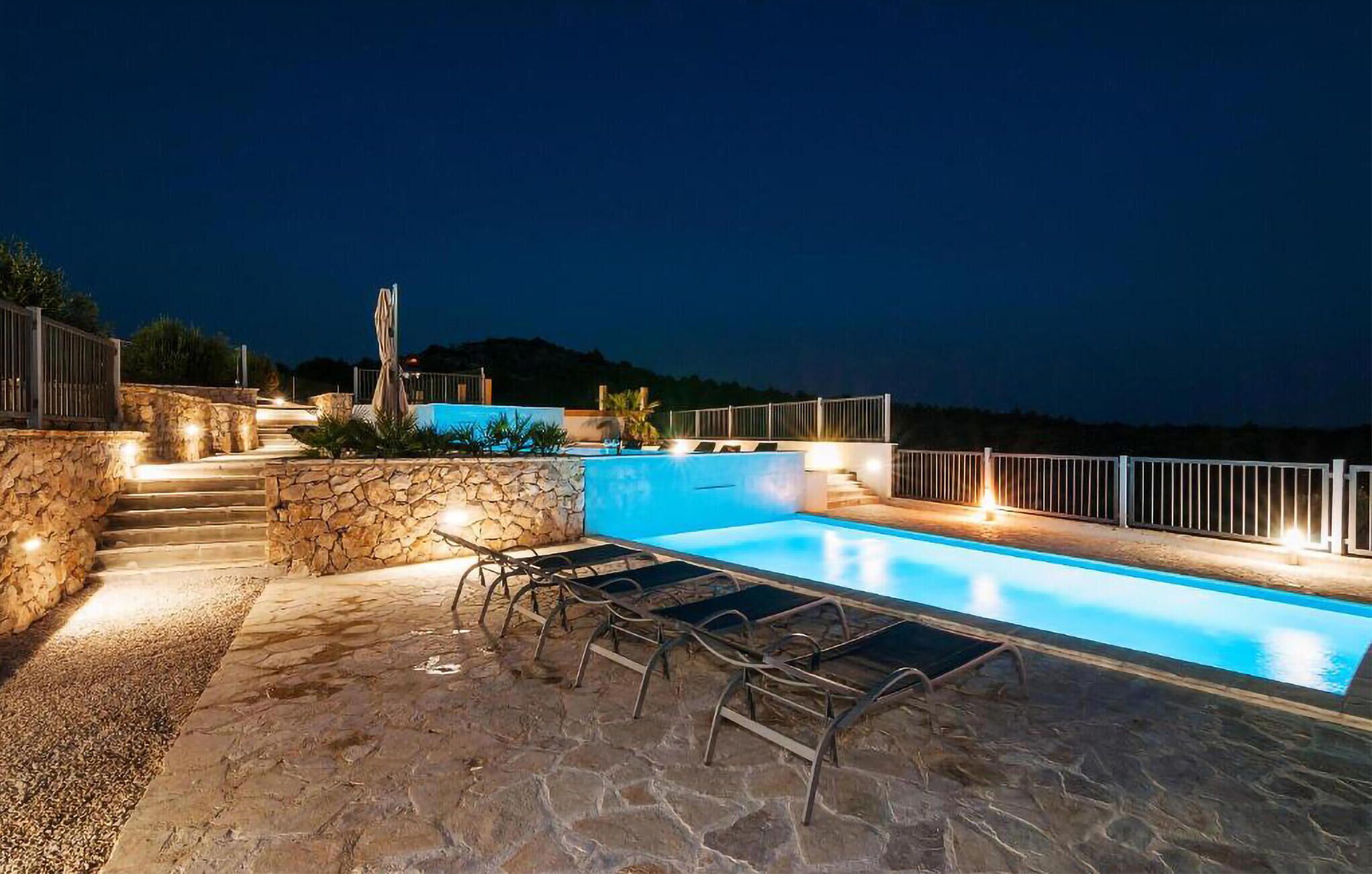 Une piscine avec des marches en pierre menant à l’eau, entourée d’une balustrade et offrant une vue sur le paysage.