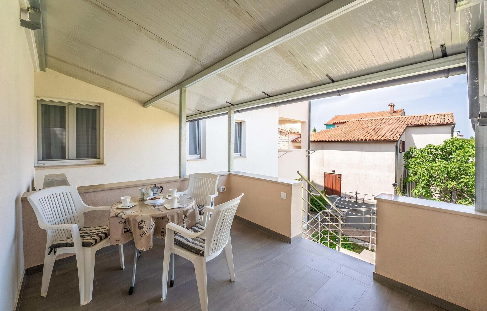 Ein Balkon mit Tisch für vier Personen, Stühlen und Blick auf die Nachbarschaft.