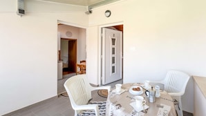 Ein Essbereich mit einem runden Tisch, weißen Stühlen und einer Kaffeekochgelegenheit. Eine Tür mit der Nummer 2 führt in einen weiteren Raum.