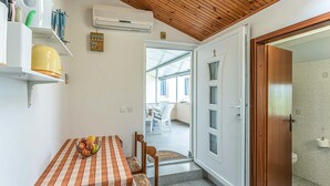 Ein Zimmer mit Holzboden, einem Tisch mit kariertem Tischtuch und einer Tür zu einem Außenbereich.