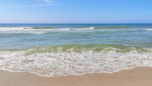 Una playa con olas acercándose a la orilla.