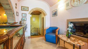 A cozy living area with a wooden staircase, a blue armchair, a small table with a plant, and a fireplace. - Pet friendly home in Mazzolla (Mazzolla)