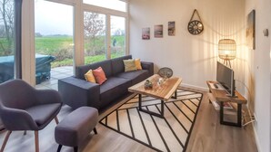 Una sala de estar moderna con un sofá, dos sillones, una mesa de centro y un televisor.