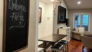 A modern kitchen with a chalkboard sign, wooden beams, and a cozy seating area.