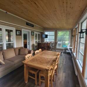 A spacious room with a wooden ceiling, a large dining table with chairs, a sofa, and a television mounted on the wall. - Large Lakehouse with hot tub. walk to public beach in Twin Lakes WI (Twin Lakes)
