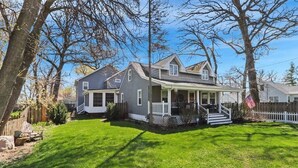 A two-story house with a front porch, a small deck, and a well-maintained lawn.