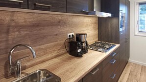 A modern kitchen with dark cabinets, a wooden countertop, a gas stove, a coffee maker, and a stainless steel sink. - Stunning home in Den Oever with WiFi (Den Oever)
