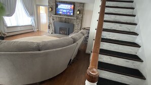 A living room with a fireplace, a television, and a staircase.