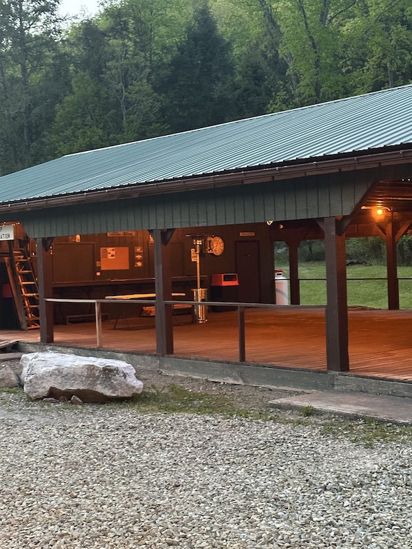 A covered outdoor area with a metal roof, wooden pillars, and a gravel path.