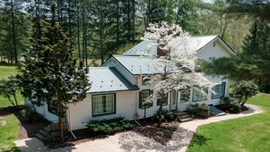 A two-story house with a metal roof, surrounded by trees and a well-maintained lawn.