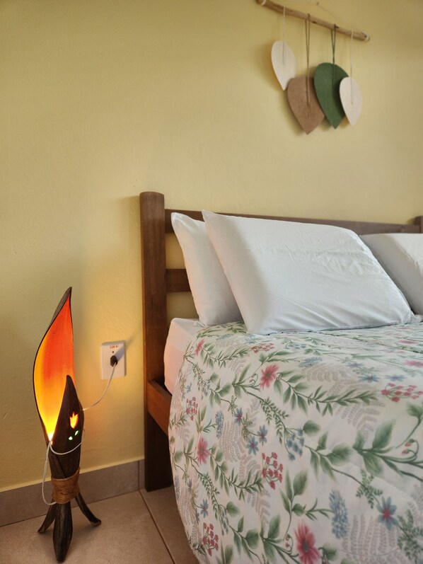 A bedroom with a bed, pillows, a wall-mounted nightlight, and a hanging hat rack. - Pousada Sertão (Alto Paraíso de Goiás)