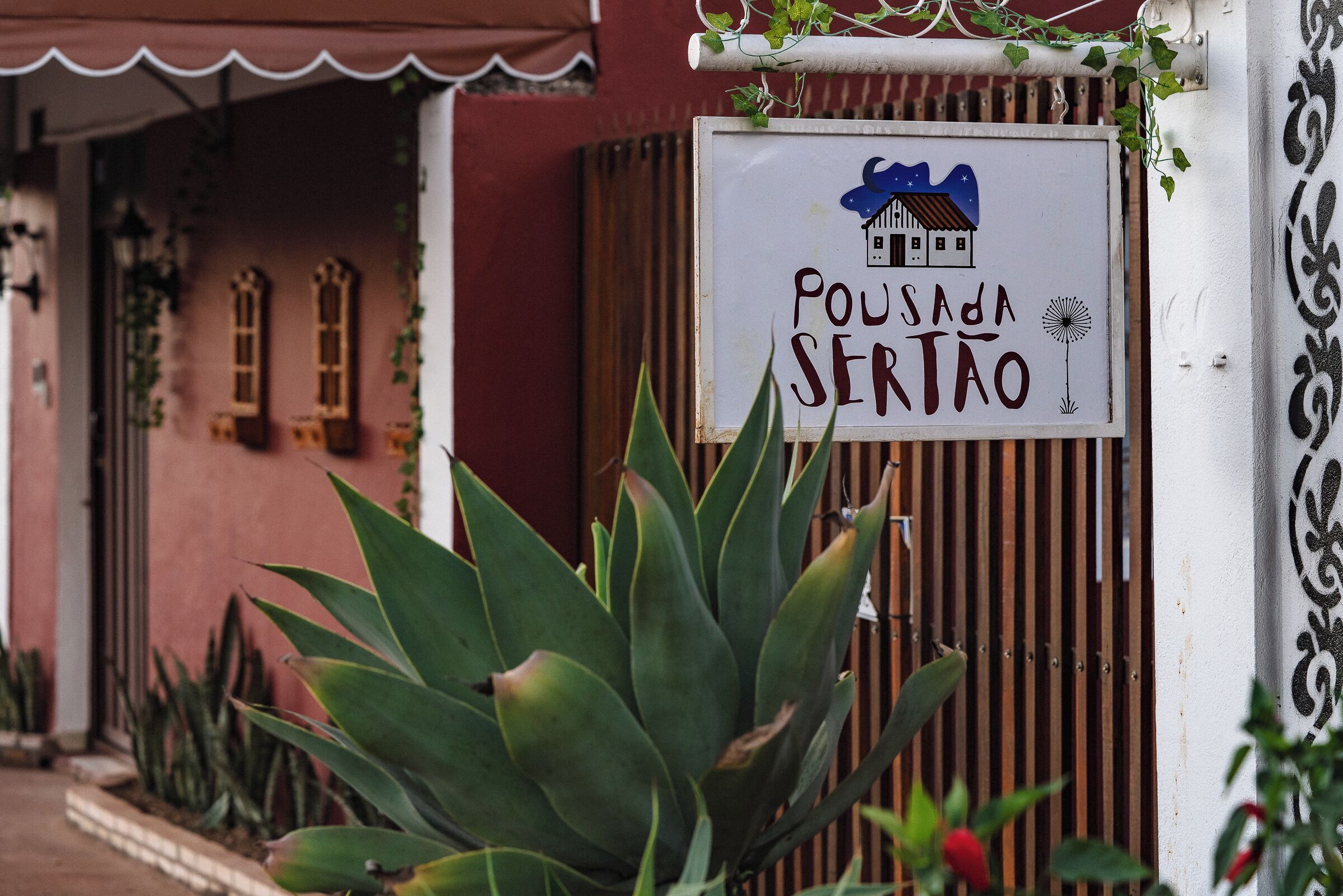 A sign with a house illustration and the text "POUSADA SERTAO" on a building facade.