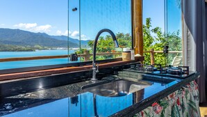 A kitchen with a large window overlooking a scenic view of mountains and a body of water.