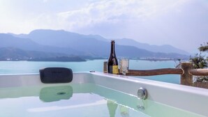 A hot tub with a view of mountains and a lake.