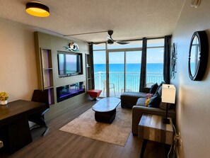 A modern living room with a large window, a flat-screen TV, a ceiling fan, and a dining area.