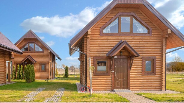 A row of log cabins with pitched roofs and large windows, surrounded by a grassy area and a paved walkway. - Pet friendly home in Jezierzany with sauna (Jezierzany)