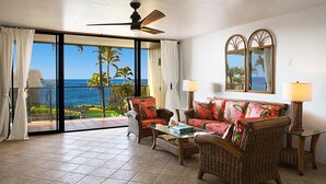 A room with a balcony, wicker furniture, a glass coffee table, and a view of the ocean. - Recently upgraded single level ocean view condo (Koloa)