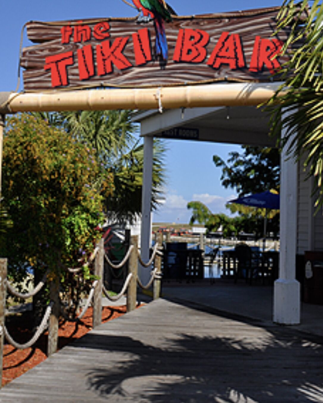 Un letrero de madera con las palabras 'The TIKI BAR' en letras rojas, que indica un área de bar.