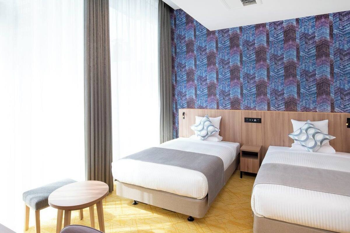 Hotellihuone, jossa on kaksi sänkyä, pieni pöytä ja tuoli.