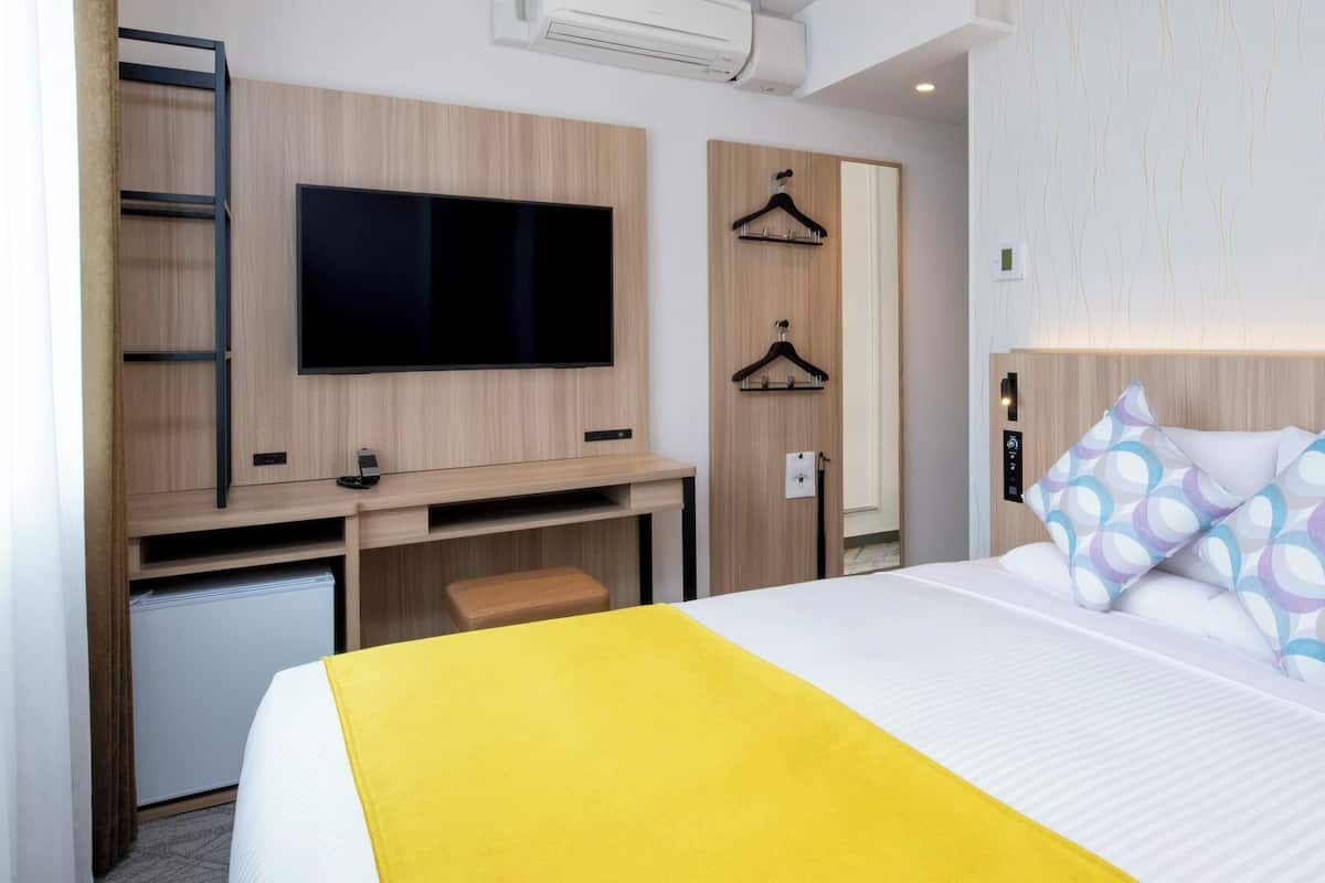 A hotel room with a bed, a TV, a desk, and a wardrobe.