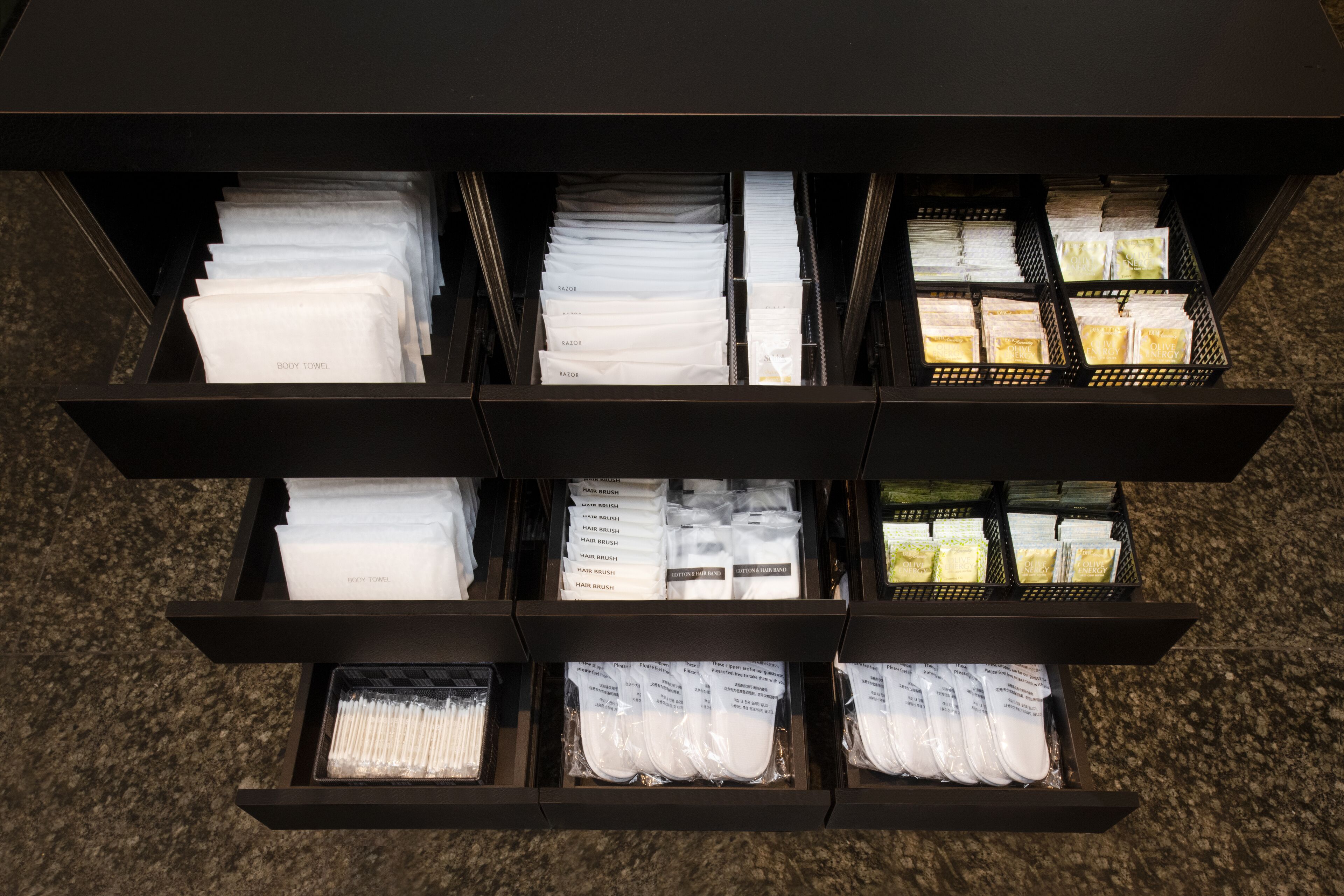 Een opbergruimte met verschillende vakken, gevuld met onder meer handdoeken, haarborstels en andere toiletartikelen.