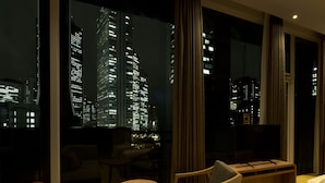 Camera d'albergo con un'ampia finestra che si affaccia su una vista notturna della città.