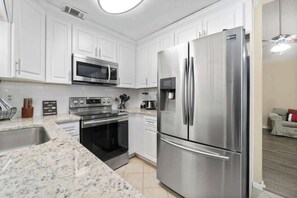 A modern kitchen with white cabinets, stainless steel appliances, and a granite countertop.
