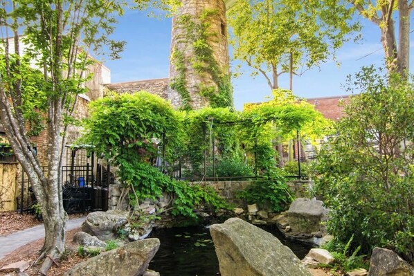 A garden with a stone bridge, trees, and a small water feature.