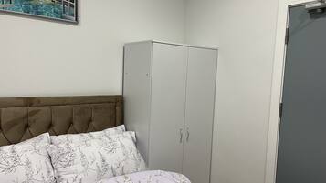 Quarto com cama, guarda-roupa e pintura de uma praia tropical.