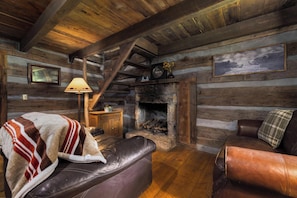 A log cabin interior with a fireplace, leather furniture, and wooden walls. - "Timber Lodge", Rustic 4BR Log Cabin + Guesthouse (Bluff City)