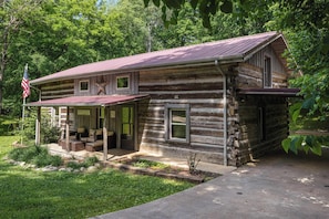 A rustic log cabin with a porch, a welcome sign, and an American flag. - "Timber Lodge", Rustic 4BR Log Cabin + Guesthouse (Bluff City)