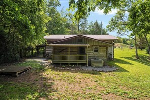 A rustic cabin with a porch, surrounded by trees and a grassy area. - "Timber Lodge", Rustic 4BR Log Cabin + Guesthouse (Bluff City)