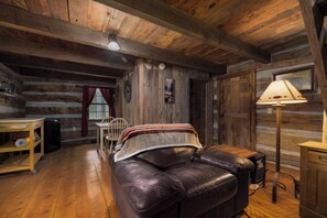 Ein Holzblockhaus-Interieur mit Ledersofa, Holzwänden, einem Tisch und einer Lampe.