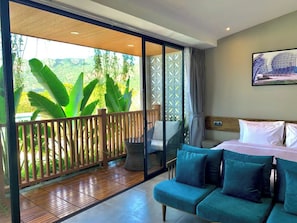 Une pièce comprenant un lit, un canapé, une petite table et un balcon doté d’une balustrade en bois et de plantes.
