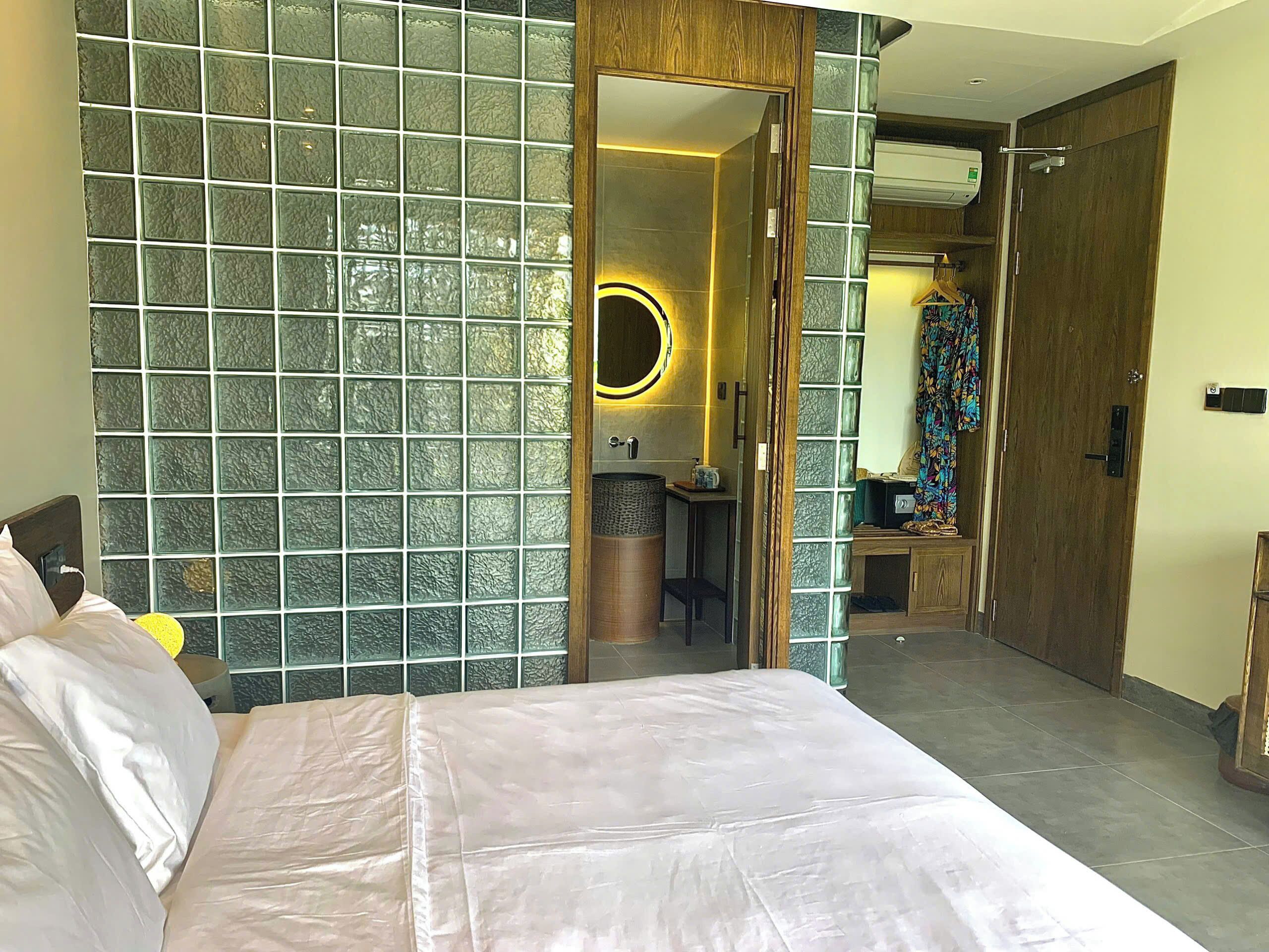 A hotel room with a bed, a bathroom with a mirror, and a door leading to another room.