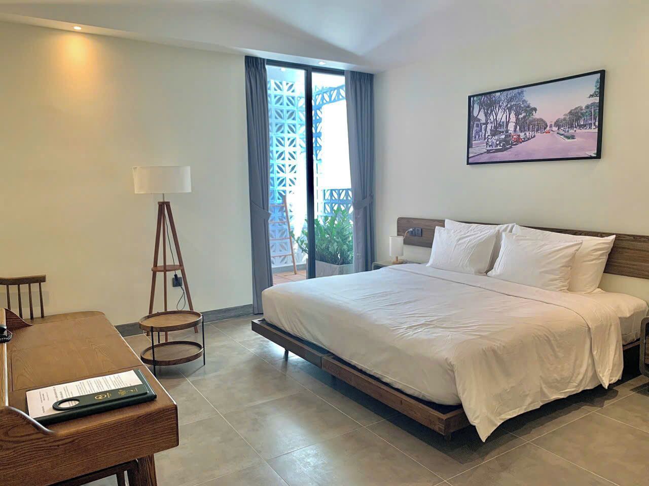 Ein Hotelzimmer mit Bett, Schreibtisch, Stuhl, Lampe und Blick ins Freie.
