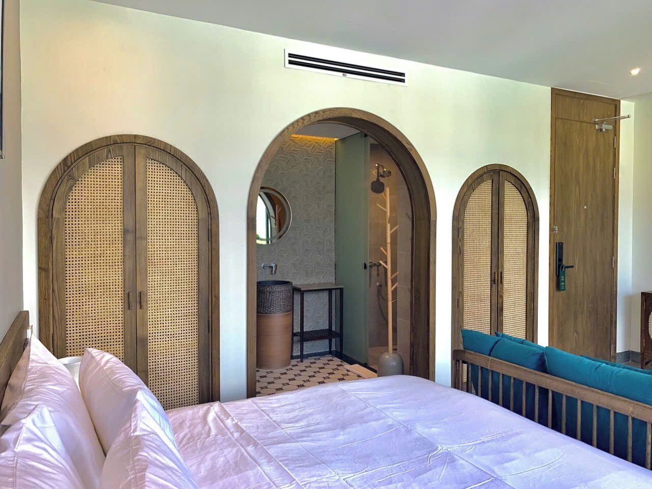 Una habitación de hotel con cama, baño con ducha y zona de estar con vistas.